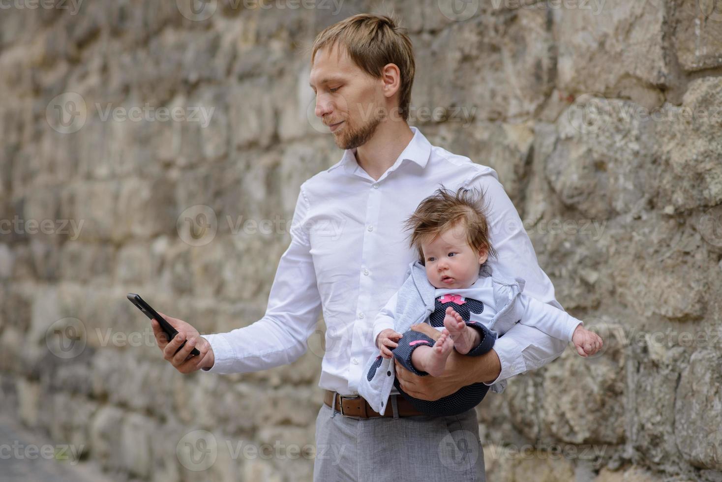 Ein junger Vater telefoniert mit einem Handy und hält seine kleine Tochter im Arm. Platz kopieren foto