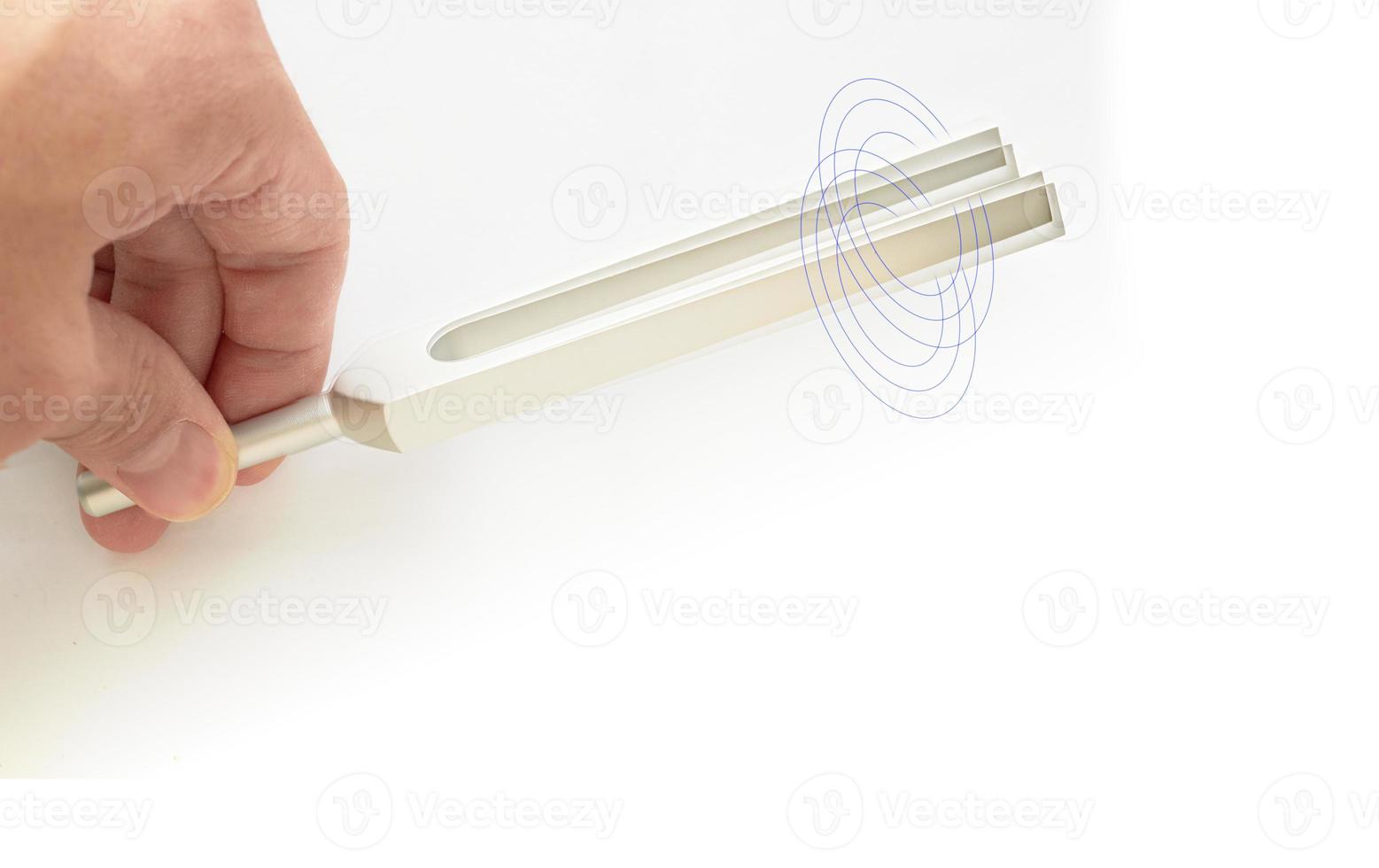hand hält stimmgabel für den ohrtest des hno-arztes oder des schallwellenherstellers auf isoliertem weißem hintergrund mit doppelbelichtung foto