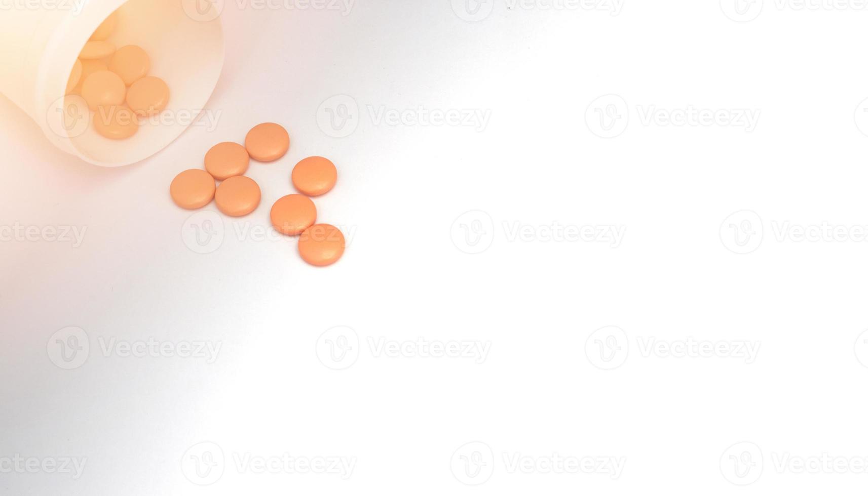 Orange beschichtete runde Arzneimitteltabletten, die sich von der Öffnung des medizinischen Plastikglases im Geschäftskonzept des medizinischen pharmazeutischen Verkäufers mit Kopierraum ausbreiten foto