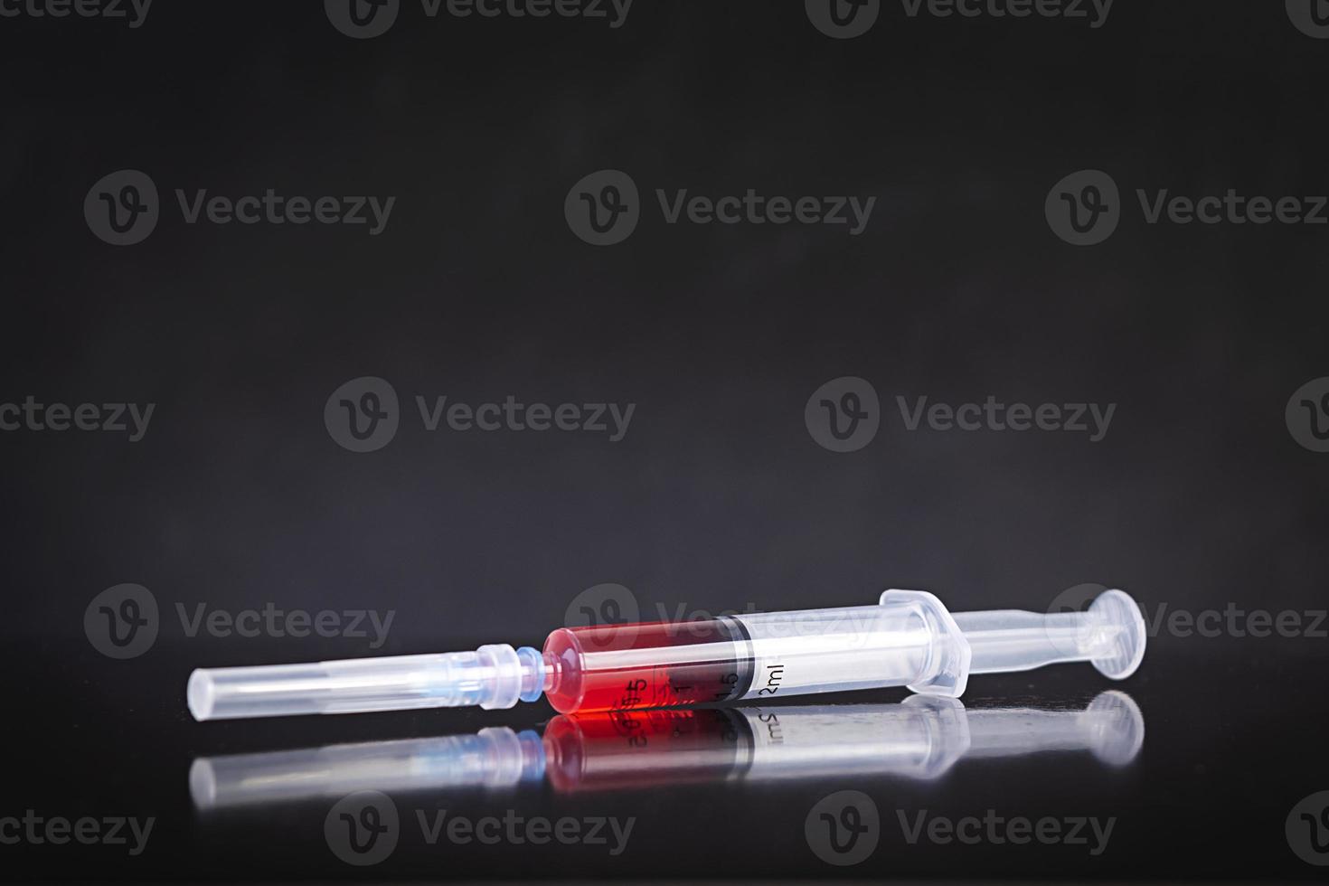 Einwegspritze und Impfstoff auf dunklem Hintergrund foto