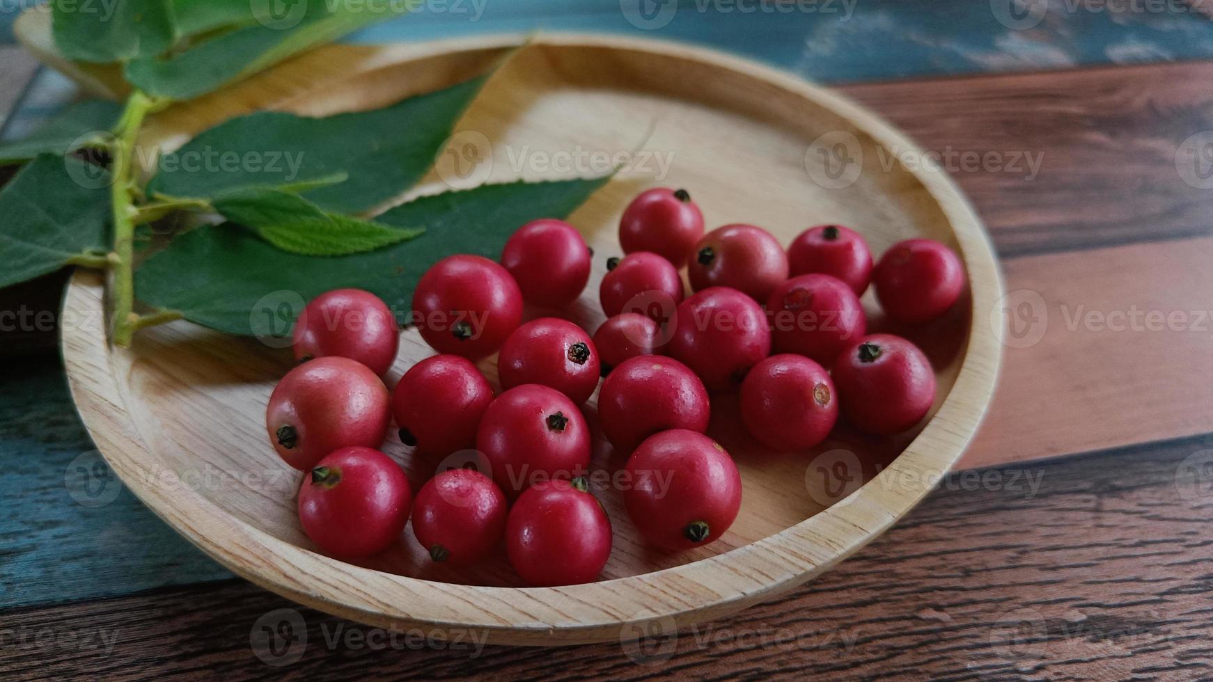 flacourtia rukam, flacourtiaceae oder takhop pak thailändischer name obstvolk in thailand auf alter holzplatte foto