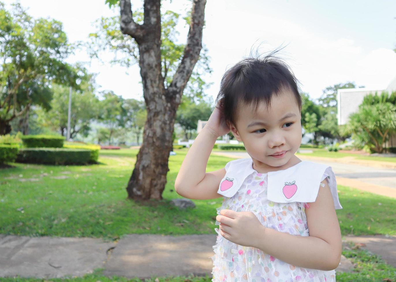 3 Jahre altes kleines asiatisches Mädchen, das sich am Kopf kratzt. foto