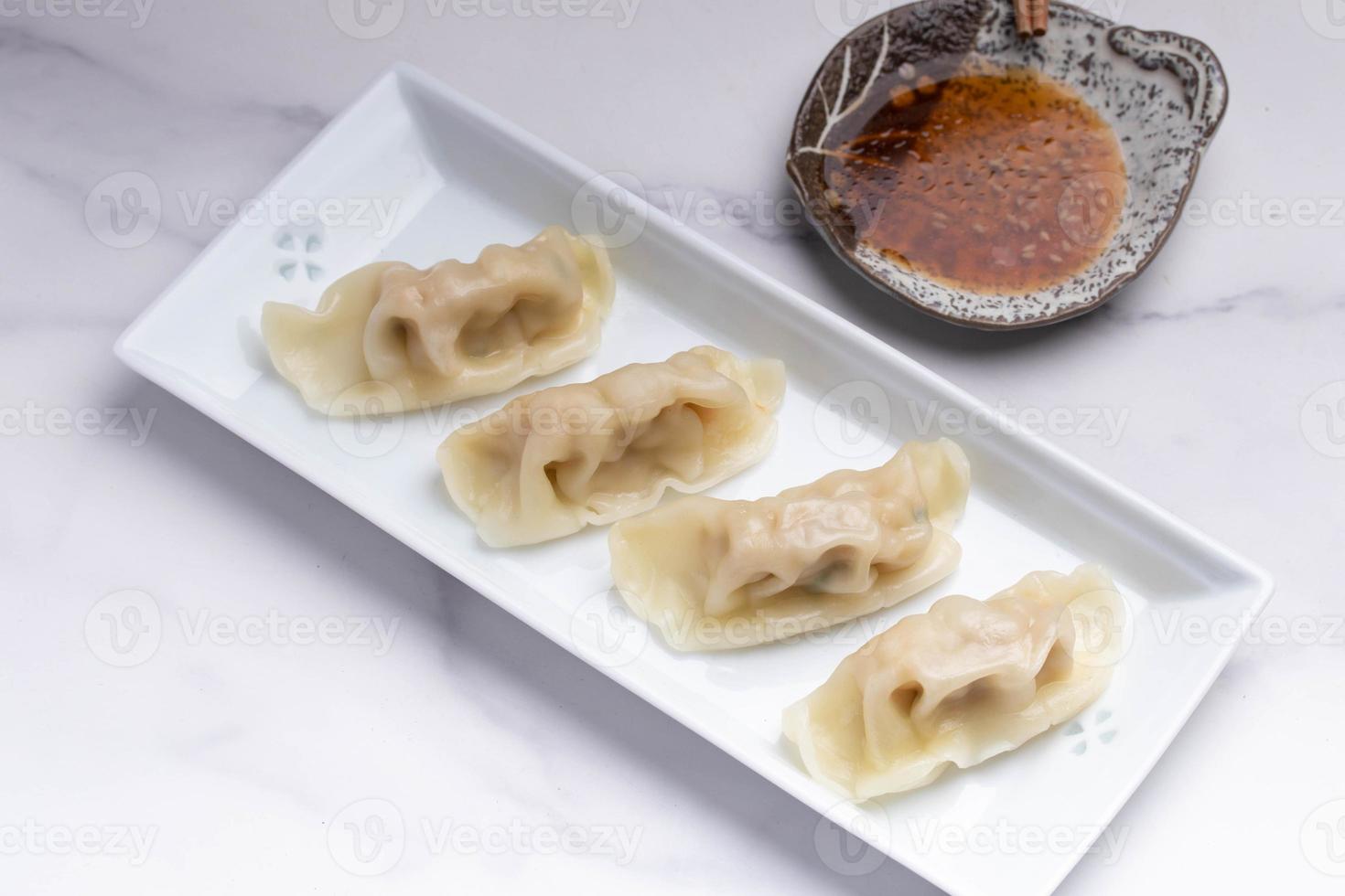 Schweinefleisch-Gyoza in einem weißen Teller mit Sojasauce foto