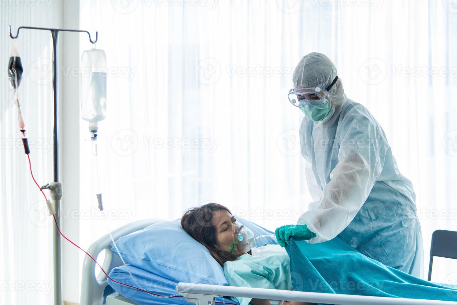 ärzte im schutzanzug, die sich um einen mit corona visrus oder covid-19 infizierten patienten kümmern, befinden sich im quarantäneraum des krankenhauses. foto