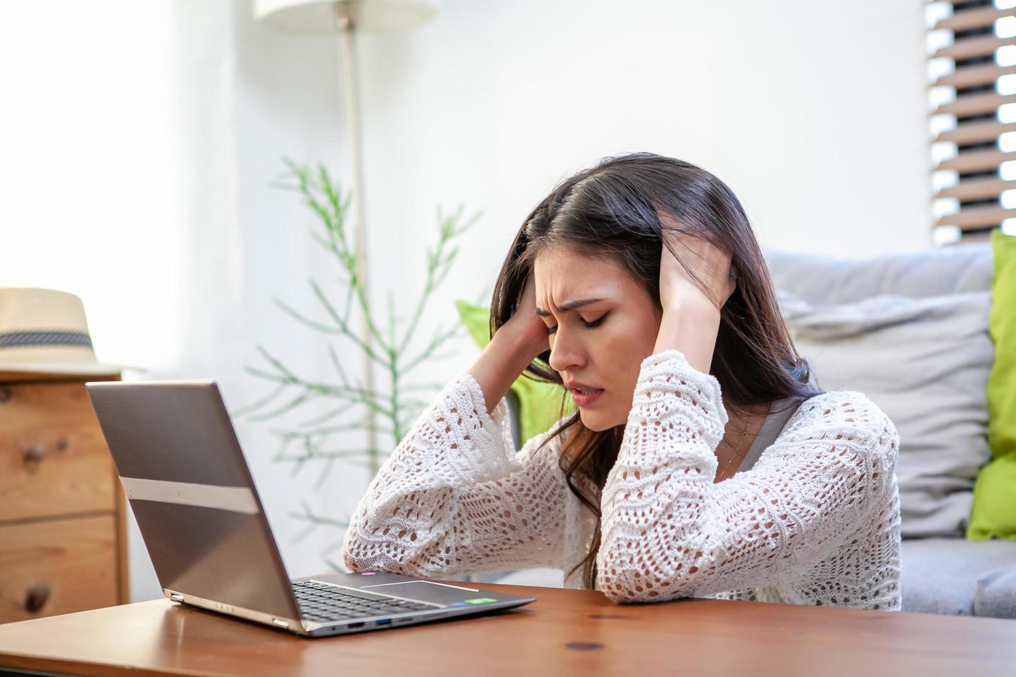 junge frau mit laptop-computer, büroangestellter müde und hat kopfschmerzen. foto