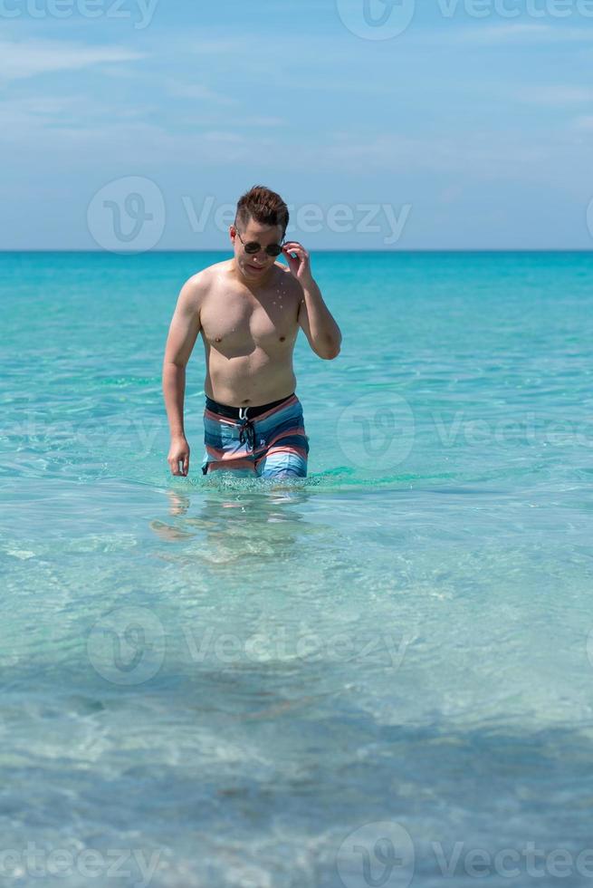 Porträt eines reifen asiatischen Mannes, der vom Meer zum Strand geht foto