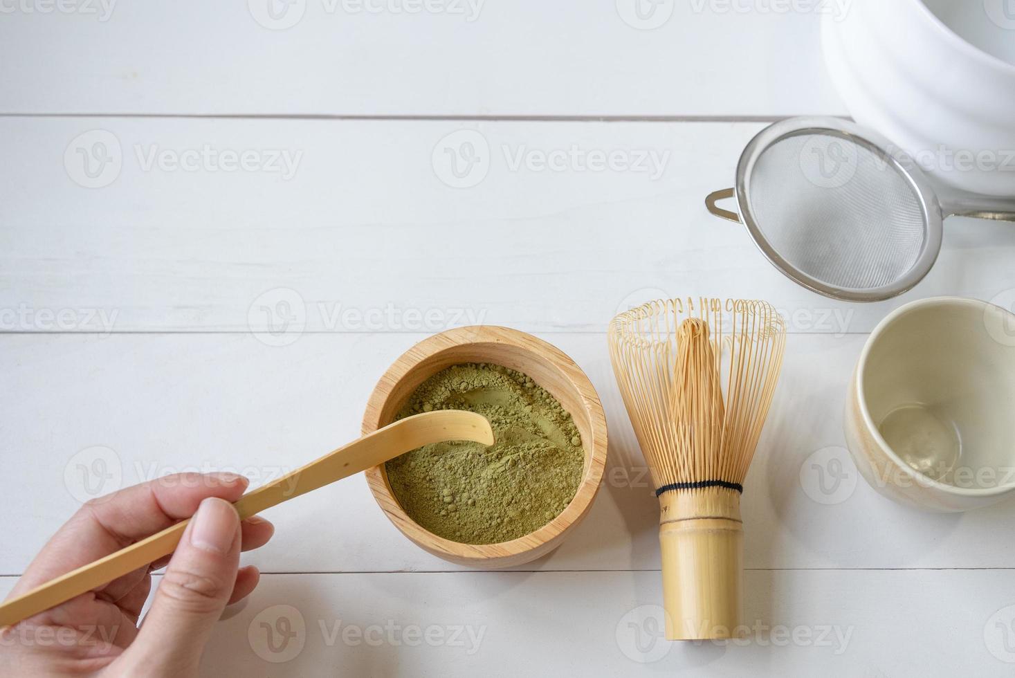 frau, die löffel verwendet, um matcha-grünteepulver zu schöpfen, um japanischen traditionellen tee zuzubereiten foto