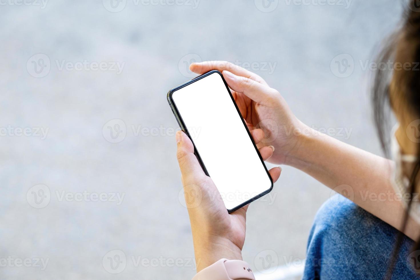 eine frau, die ein handy mit einem leeren weißen bildschirm hält. Der leere Bereich auf dem weißen Bildschirm kann verwendet werden, um eine Nachricht zu schreiben oder ein Bild zu platzieren. foto