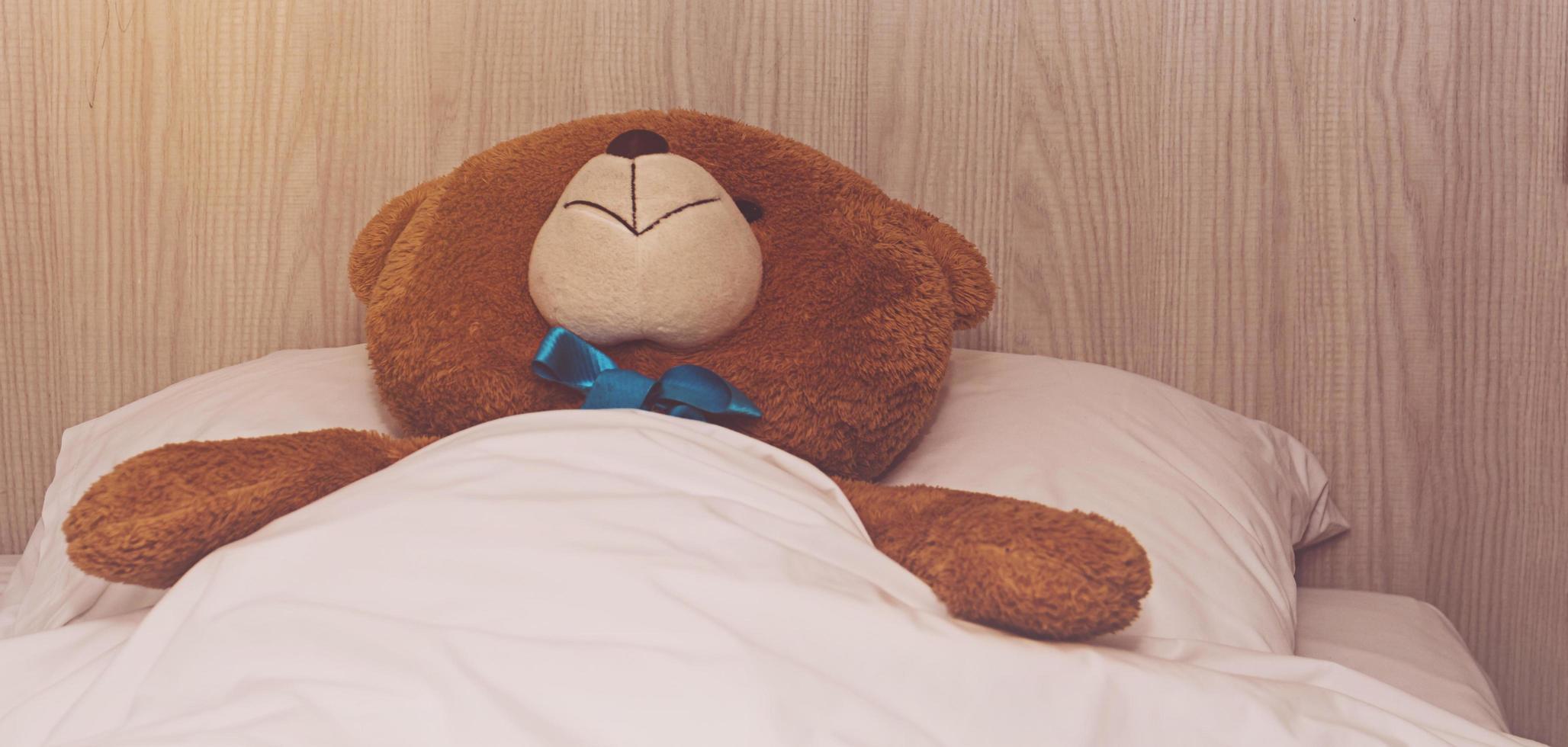 Teddybär liegt im Bett foto