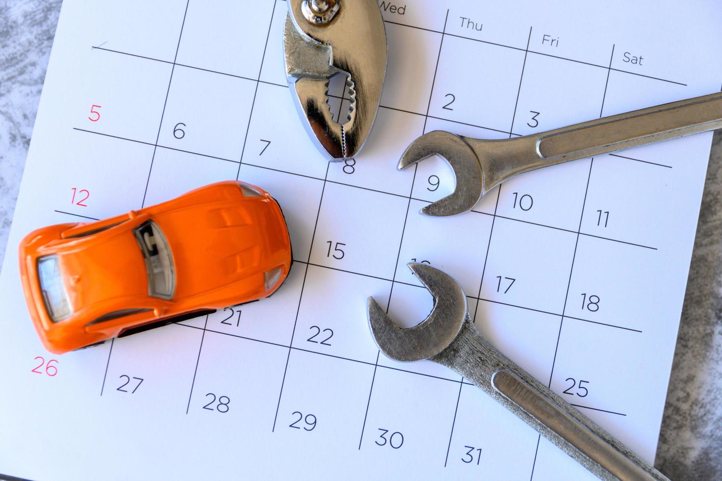 Schraubenschlüssel und Auto im Kalender mit Zahlen. Reparaturkonzept foto