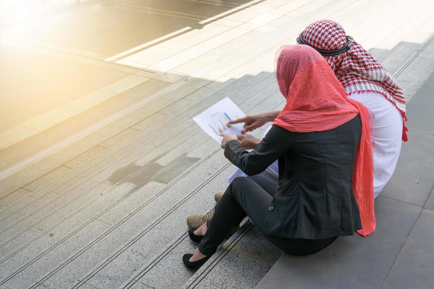 arabischer geschäftsmann und geschäftsfrau überprüfen diagramm auf papier, finanzkonzept foto