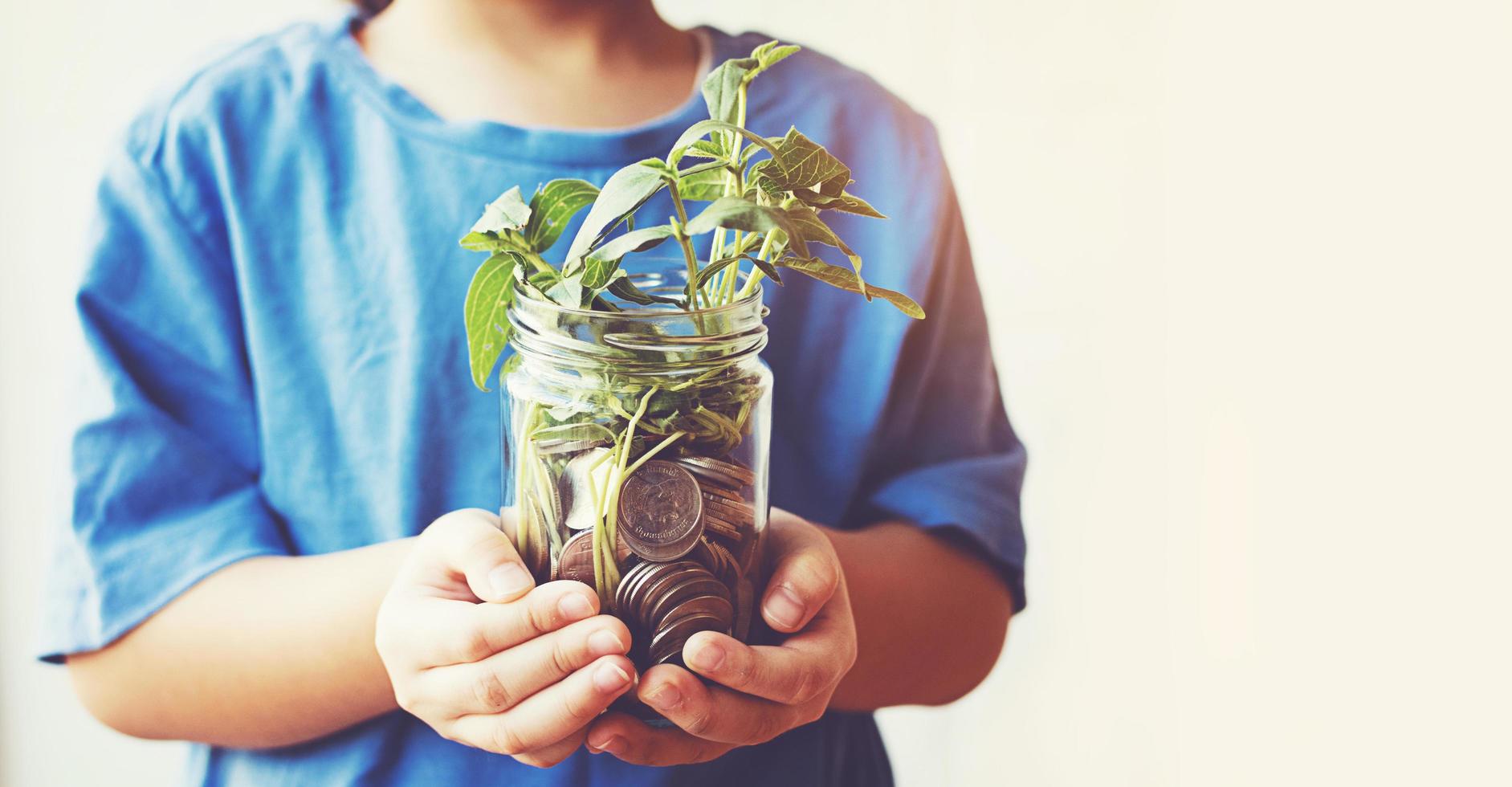 Kind spart Geld in der Flasche Geld, das als Baum aufwächst foto