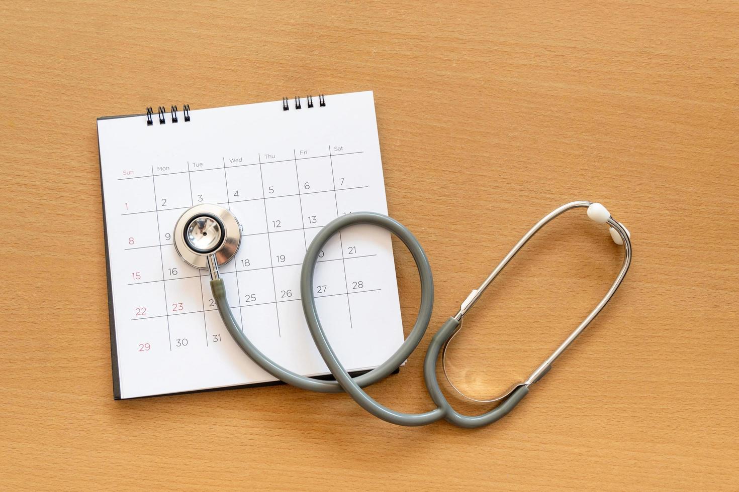 Stethoskop und Kalender auf Holztisch, Zeitplan zur Überprüfung des gesunden Konzepts foto