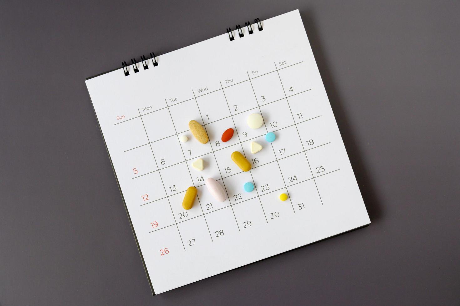 Pillen auf einem Kalenderhintergrund. Konzept Gesundheitswesen foto