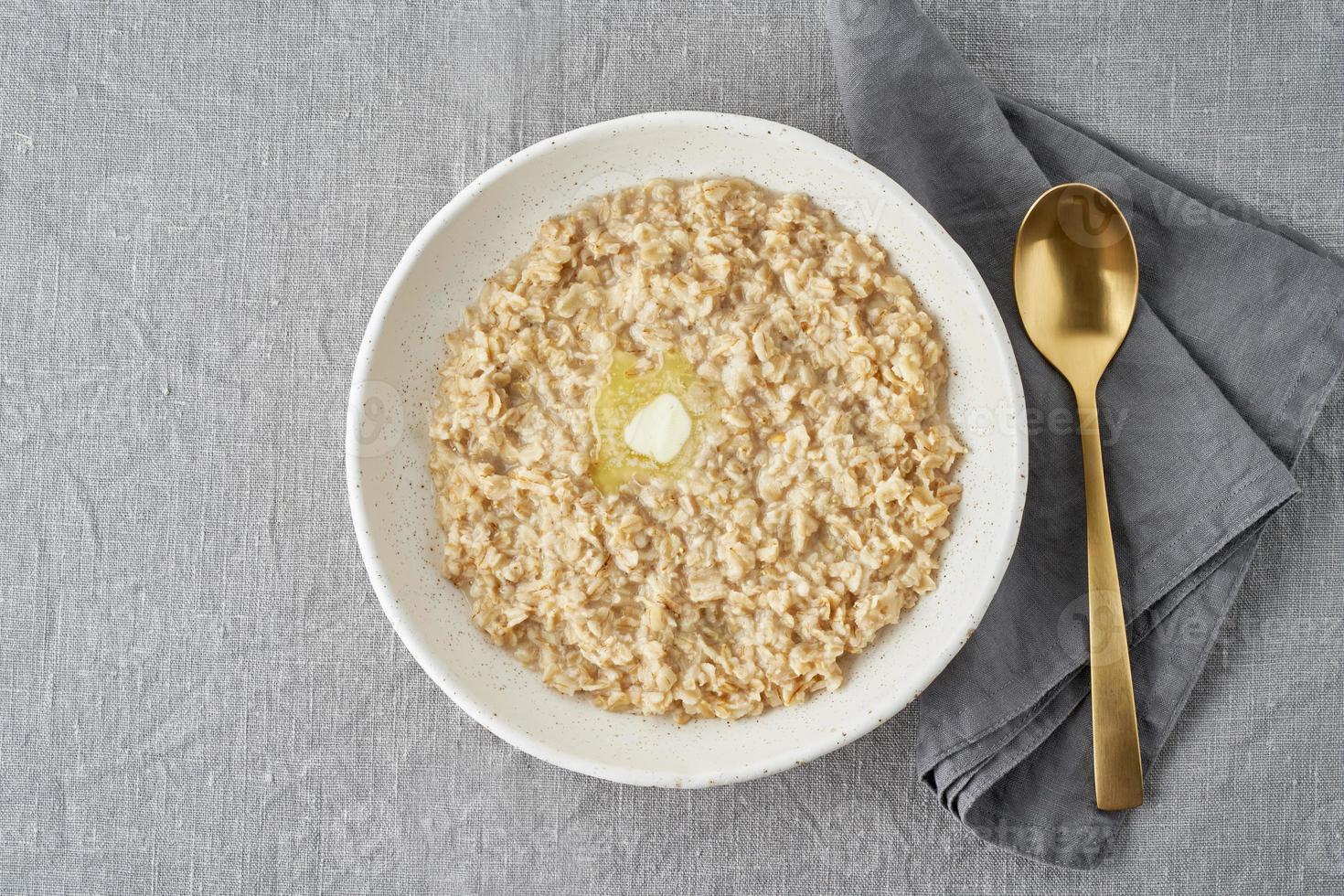 ganze Haferflocken, große Schüssel Haferbrei mit Butter zum Frühstück, Morgenmahlzeit. foto