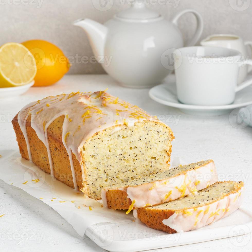 Zitronenbrot mit zuckersüßer Glasur überzogen und mit Zitronenschale bestreut. Stück Kuchen mit Zitrusfrüchten foto