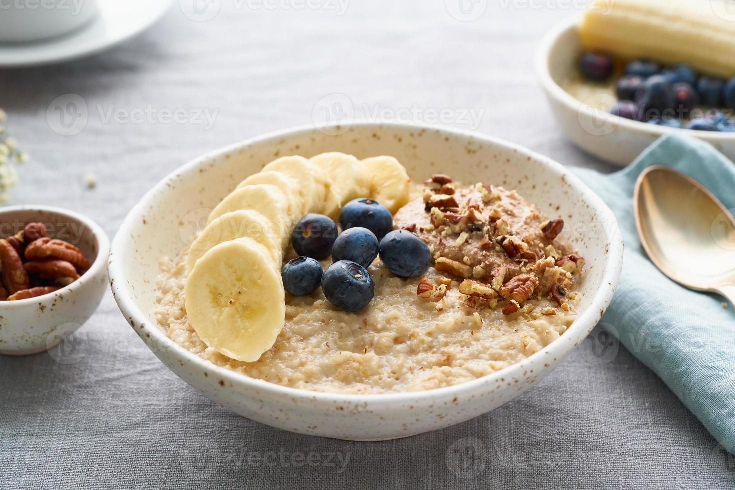 ganze Haferflocken, große Schüssel Haferbrei mit Banane, Heidelbeeren, Nüssen zum Frühstück, foto