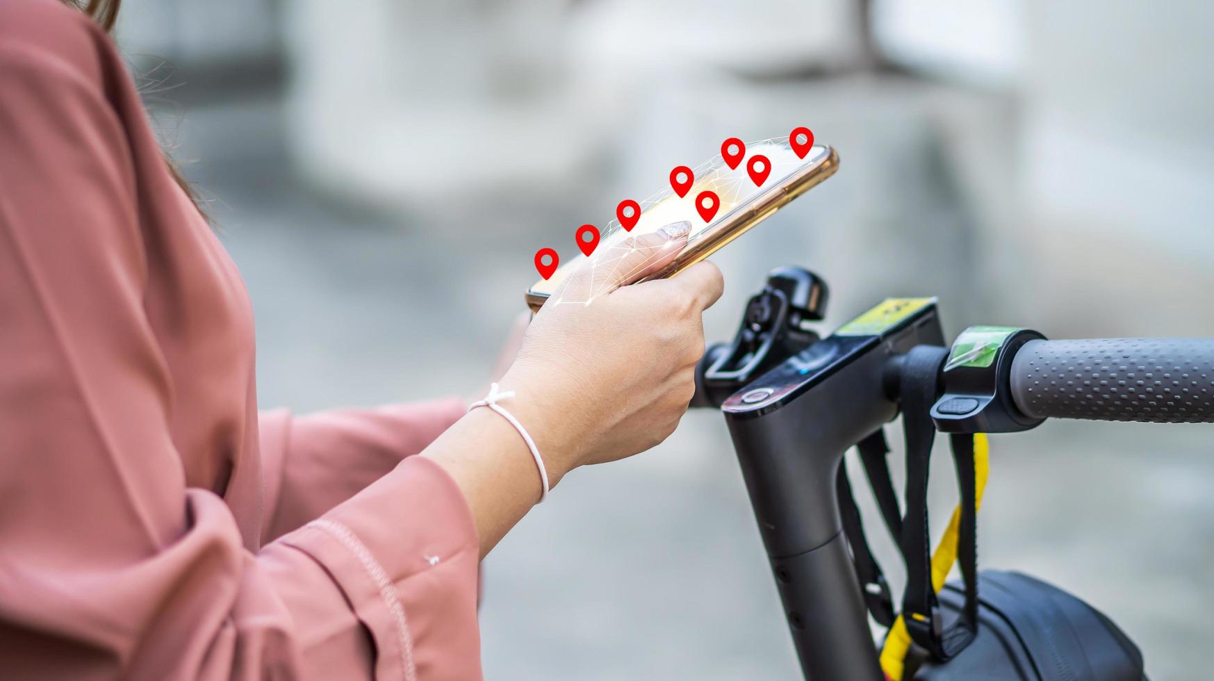 Nahaufnahme einer Frau, die Smartphone-Hände hält und die Karten-App verwendet, bevor sie mit dem Elektroroller in der Stadt fährt foto