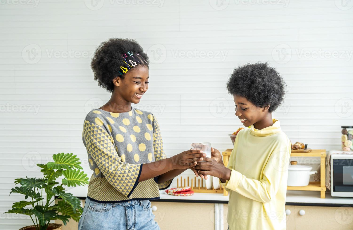 süße kleine kinder, die in der küche mit milch frühstücken, afrikanisch-amerikanischer süßer junge, der milch mit seiner schwester trinkt, essen- und getränkekonzept mit kopierraum foto