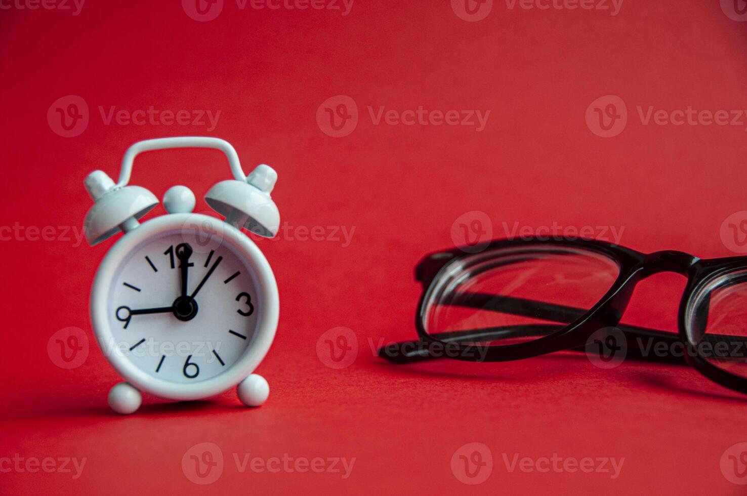 wecker zeigt um 9 uhr mit brille und rotem hintergrund. Raumkonzept kopieren foto