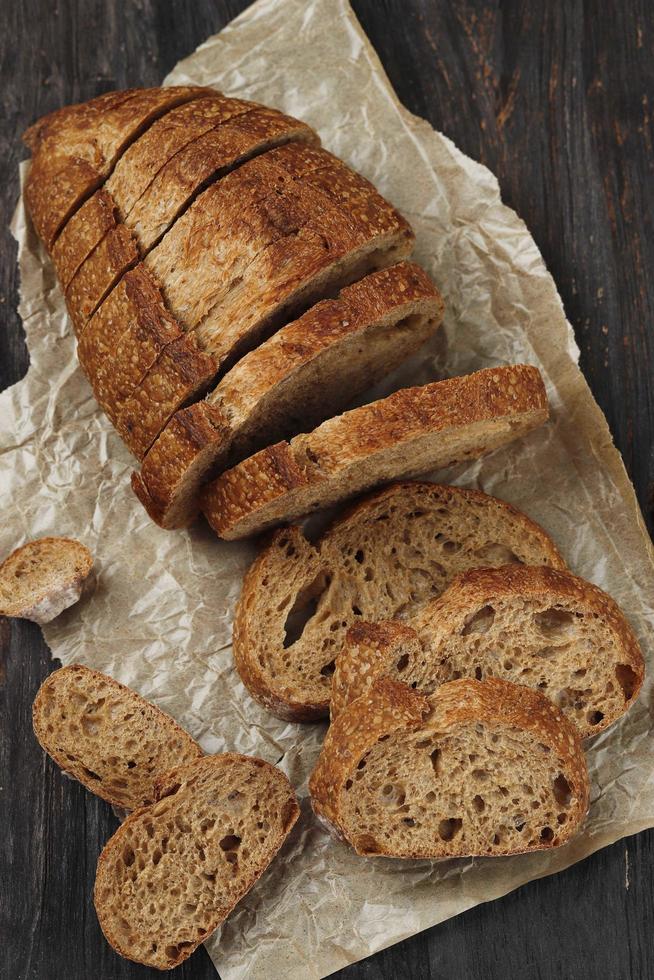 traditionelles Dinkel-Sauerteigbrot in Scheiben geschnitten auf rustikalem Holzhintergrund foto