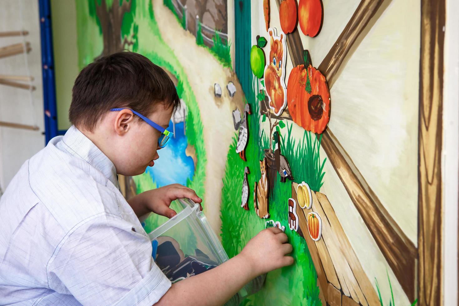 redaktionell. ein Teenager mit Behinderungen spielt mit Bildern auf einer Magnettafel. Down-Syndrom, Autismus. Rehabilitationszentrum, Schule für besondere Kinder. Kaluga, Russland, 21.06.2018 foto