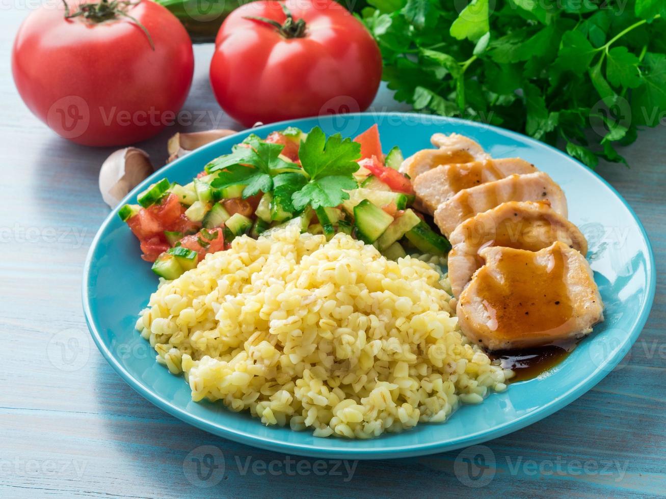 Putenfleisch, gebraten mit Teriyaki-Sauce, Gurkensalat, Tomate, Gemüse, Beilage Bulgur, Seitenansicht foto