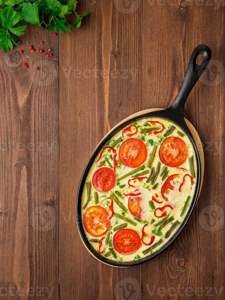 traditionelles italienisches essen, frittata mit gemüse in einer gusseisernen pfanne. vertikales Layout, Draufsicht, Leerzeichen für Text foto