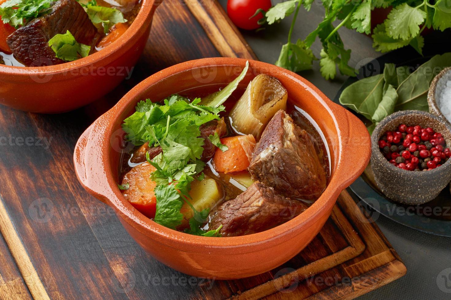 Gulasch mit großen Stücken Rindfleisch und Gemüse. langsames Schmoren, Kochen in zwei Töpfen oder gusseiserner Pfanne foto