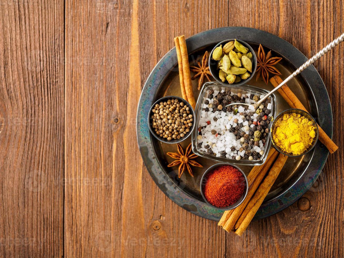 orientalisches Gewürzset - Koriander, roter Pfeffer, Kurkuma, Zimt, Sternanis, verschiedene Gewürze in Metallbechern, auf braunem, dunklem Holztisch, Draufsicht, Makro, leerer Raum. foto