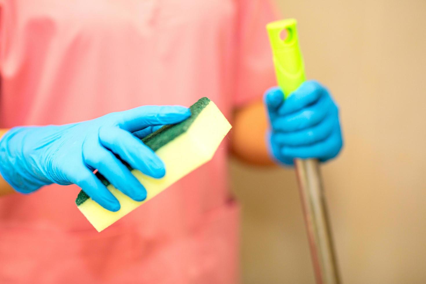 Person, eine Hand in einem blauen Gummihandschuh auf dem Bild, entfernt und wäscht das Waschbecken im Badezimmer foto