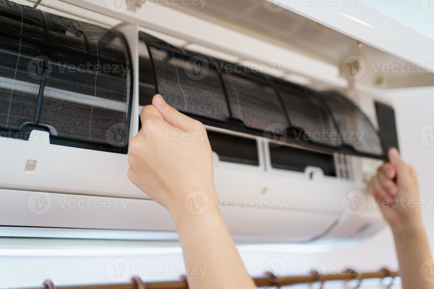 asiatische frau, die einen schmutzigen und staubigen klimaanlagenfilter in ihrem haus reinigt. Hausfrau, die einen staubigen Klimaanlagenfilter entfernt. foto