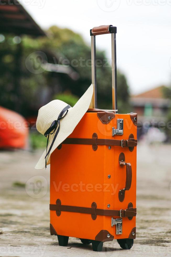 Nahaufnahme eines orangefarbenen Vintage-Koffers mit Sommerhut für Reise- oder Urlaubskonzept foto