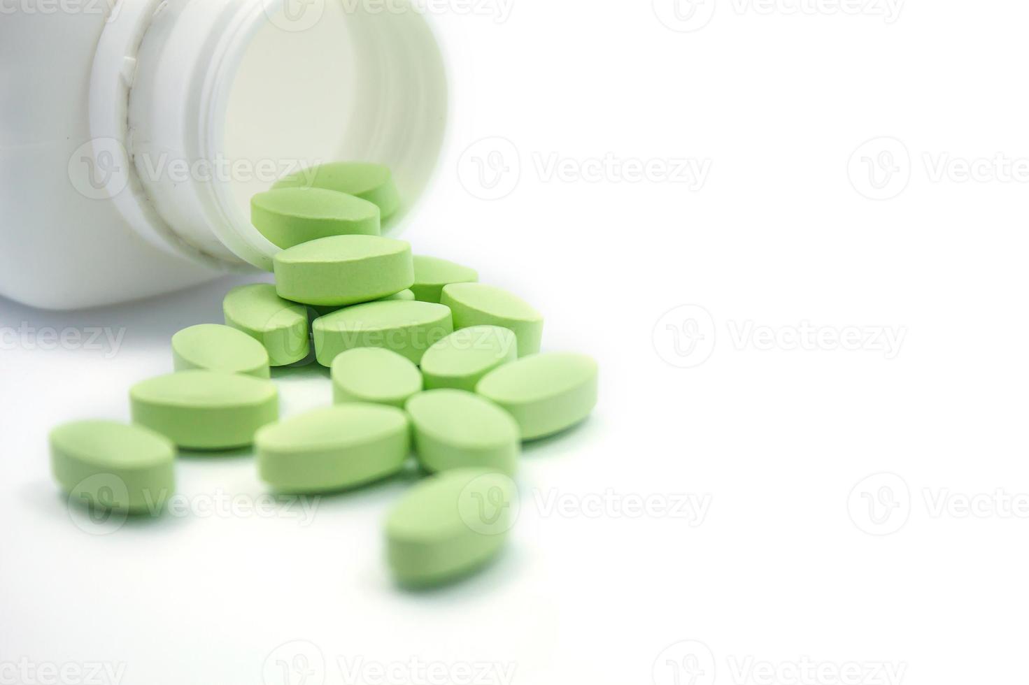 grüne Pillen und Tablettenfläschchen auf weißem Hintergrund foto