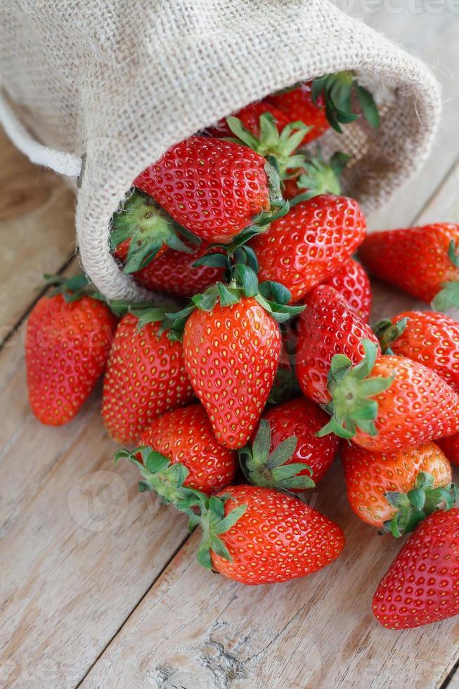 Erdbeeren im kleinen Sack auf Holztischhintergrund foto