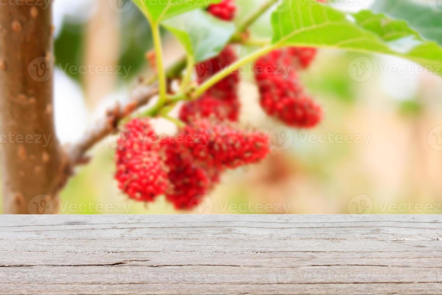 Holztisch mit rotem Maulbeerhintergrund foto