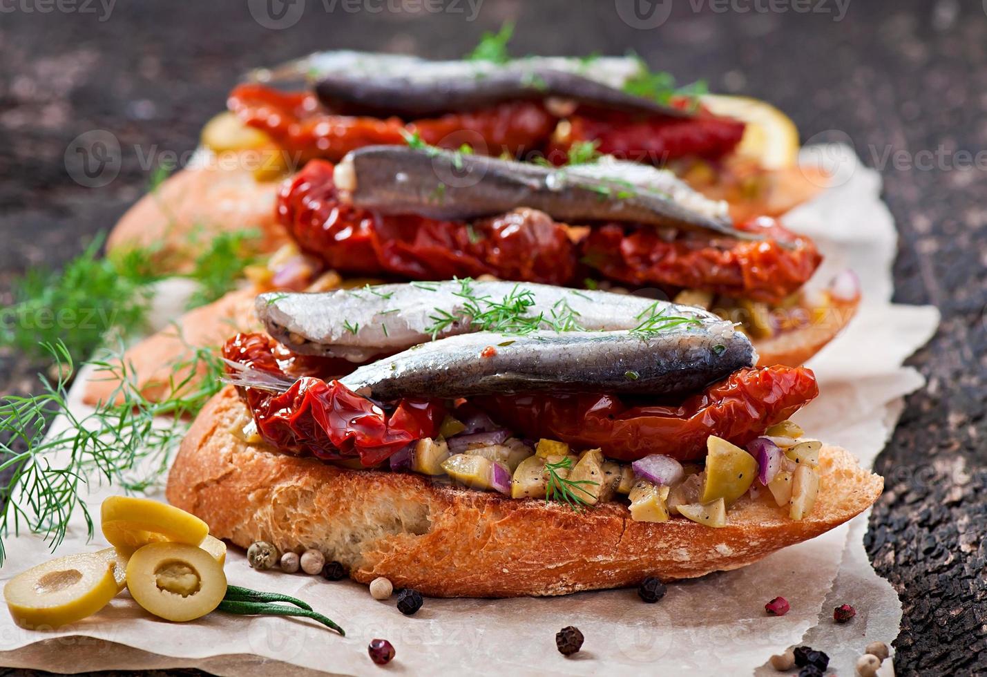 Crostini mit Sardellen, Oliven und sonnengetrockneten Tomaten foto