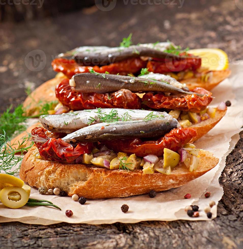 Crostini mit Sardellen, Oliven und sonnengetrockneten Tomaten foto