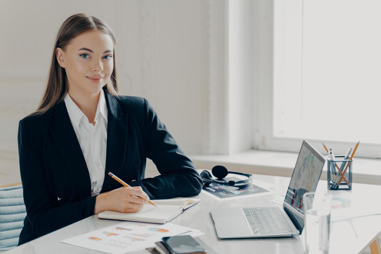 lächelnde Geschäftsfrau, die in einem modernen Büro arbeitet foto