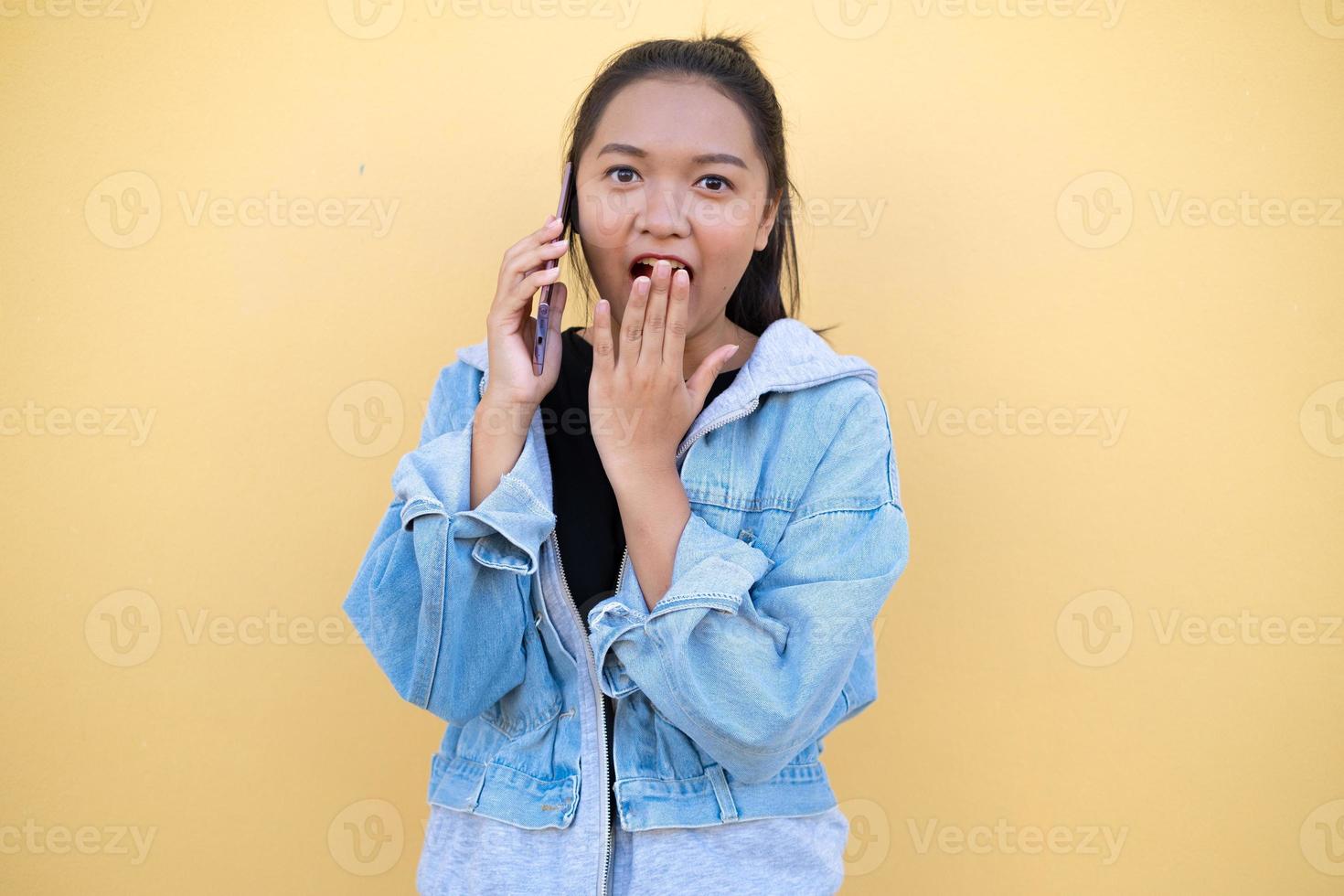 Portrait junge Mädchen tragen Jacke Jeans und verwenden Handy auf braunem Hintergrund. foto