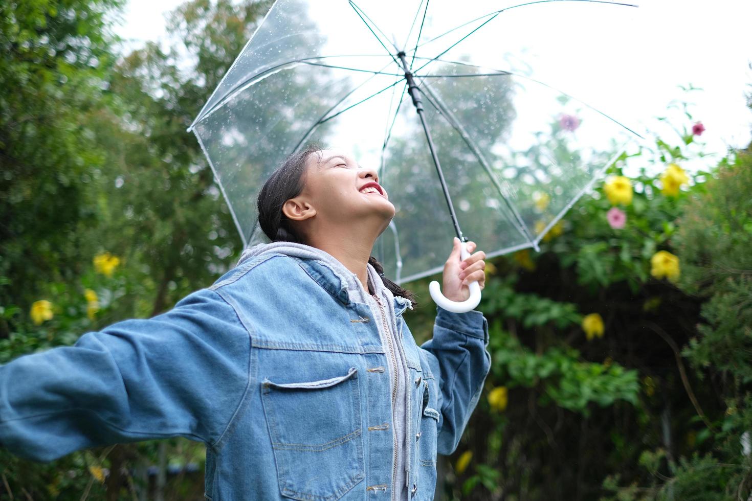 Lächeln Sie junges Mädchen, das Spaß im Regen hat. foto