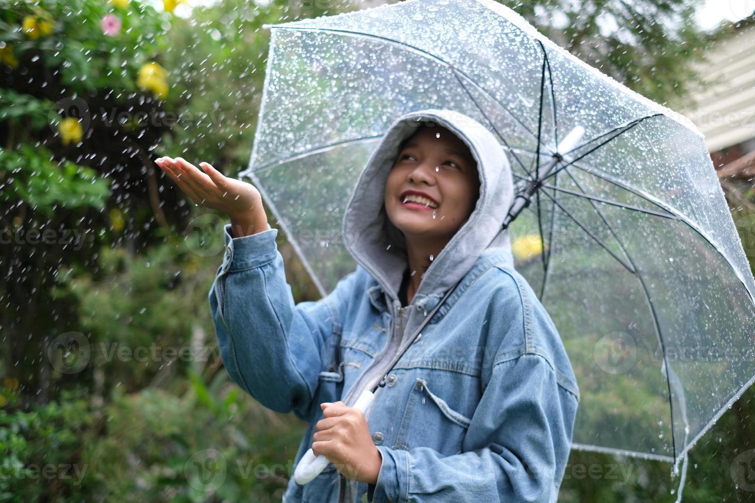 Lächeln Sie junges Mädchen, das Spaß im Regen hat. foto