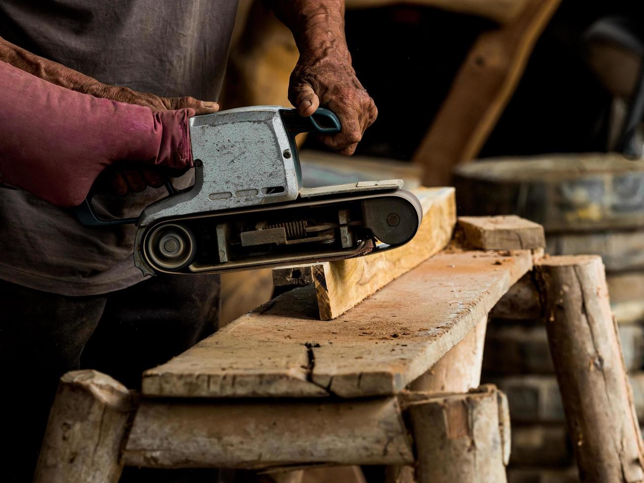 Professionelle Techniker in der Fabrik verwenden Elektrowerkzeuge, um das Holz zu polieren foto