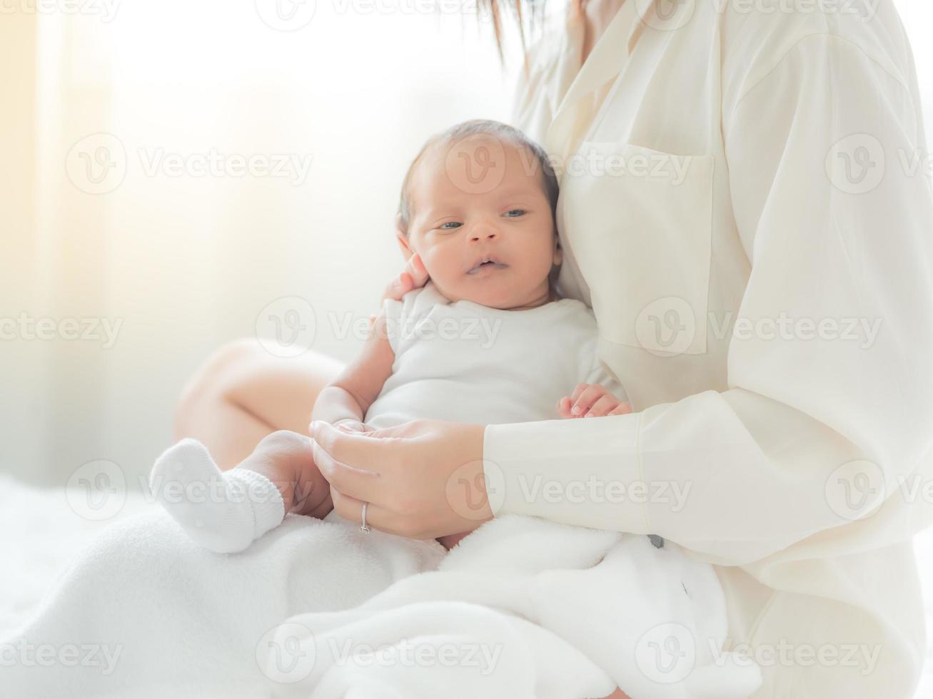 eine schöne asiatische frau legt ihr neugeborenes baby glücklich und mit liebe auf ihren körper foto