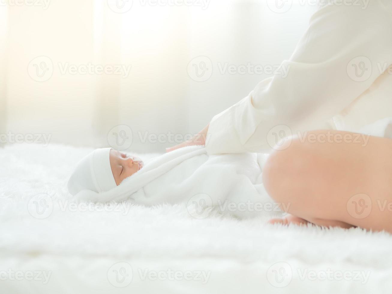 eine schöne asiatin legt ihr neugeborenes baby auf ihr bett foto