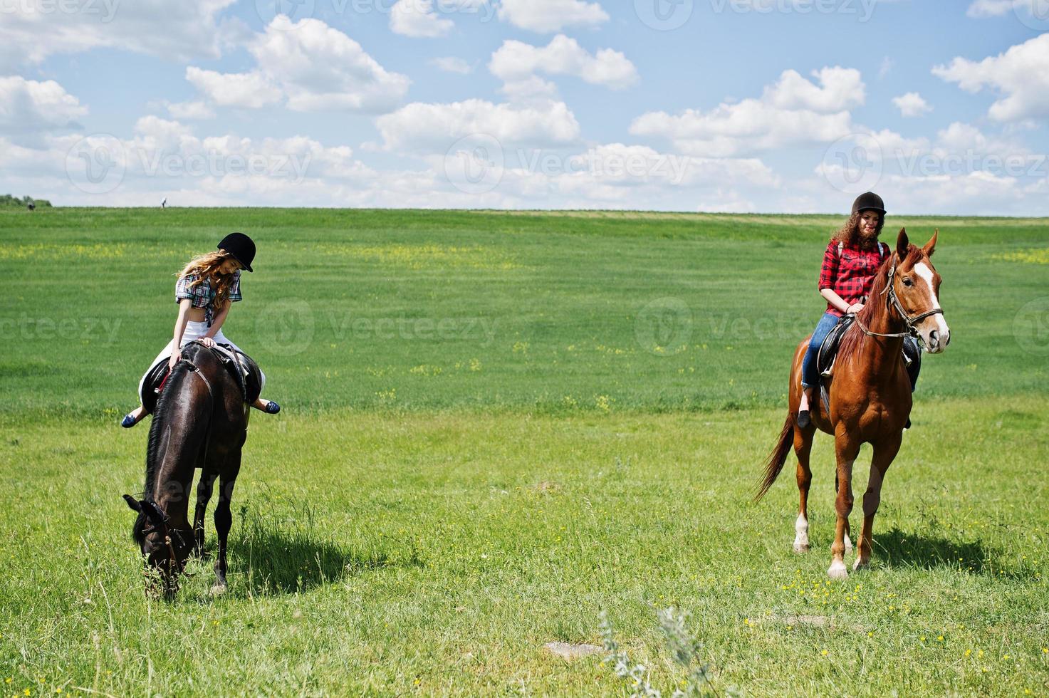 Schleppen Sie junge hübsche Mädchen, die an sonnigen Tagen auf einem Feld reiten foto