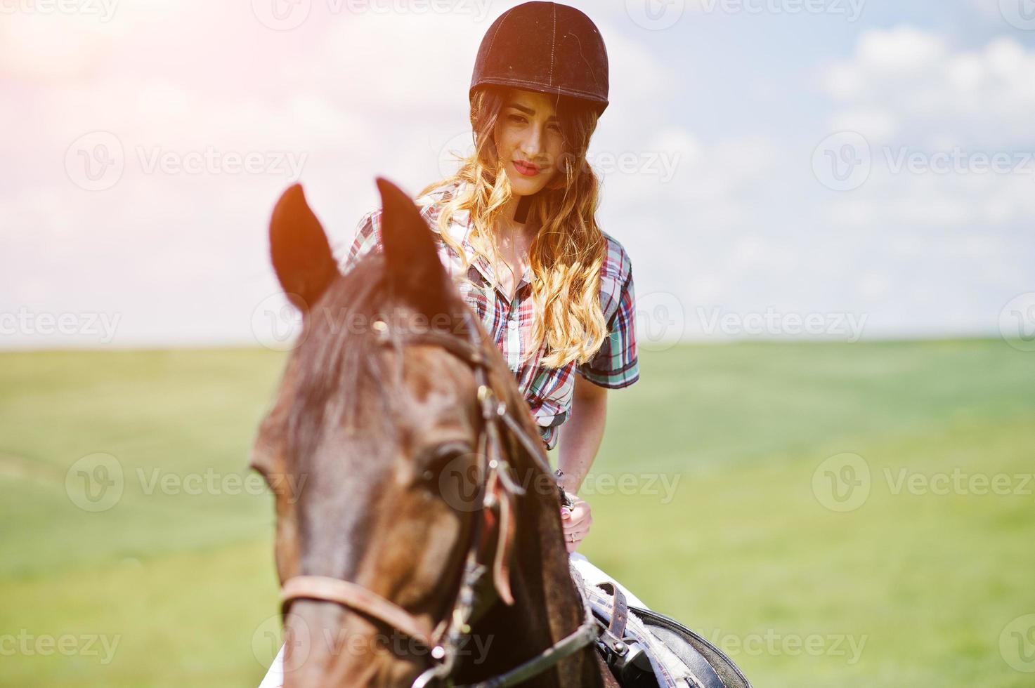 junges hübsches mädchen, das an einem sonnigen tag auf einem feld reitet. foto