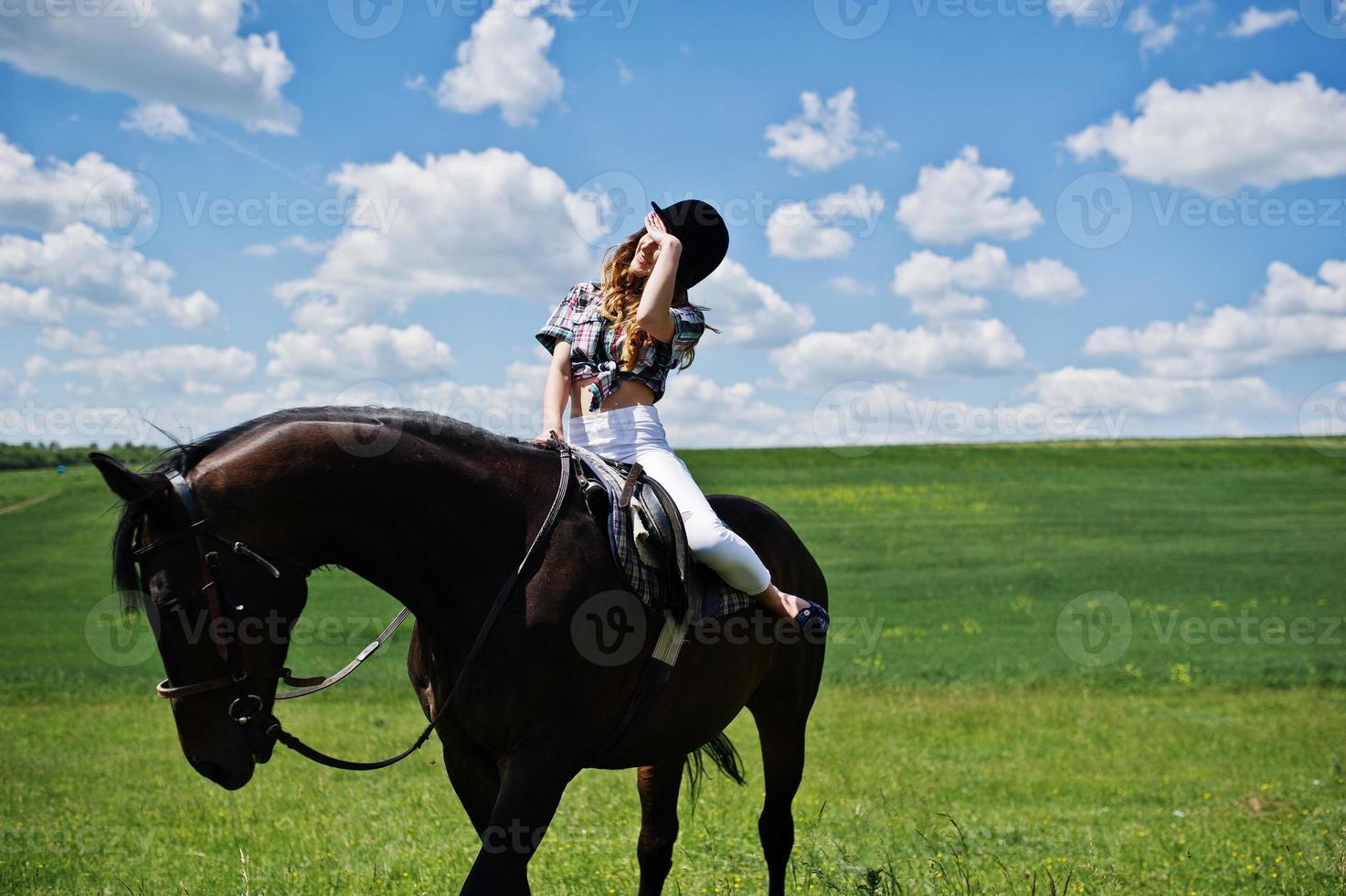 junges hübsches mädchen, das an einem sonnigen tag auf einem feld reitet. foto