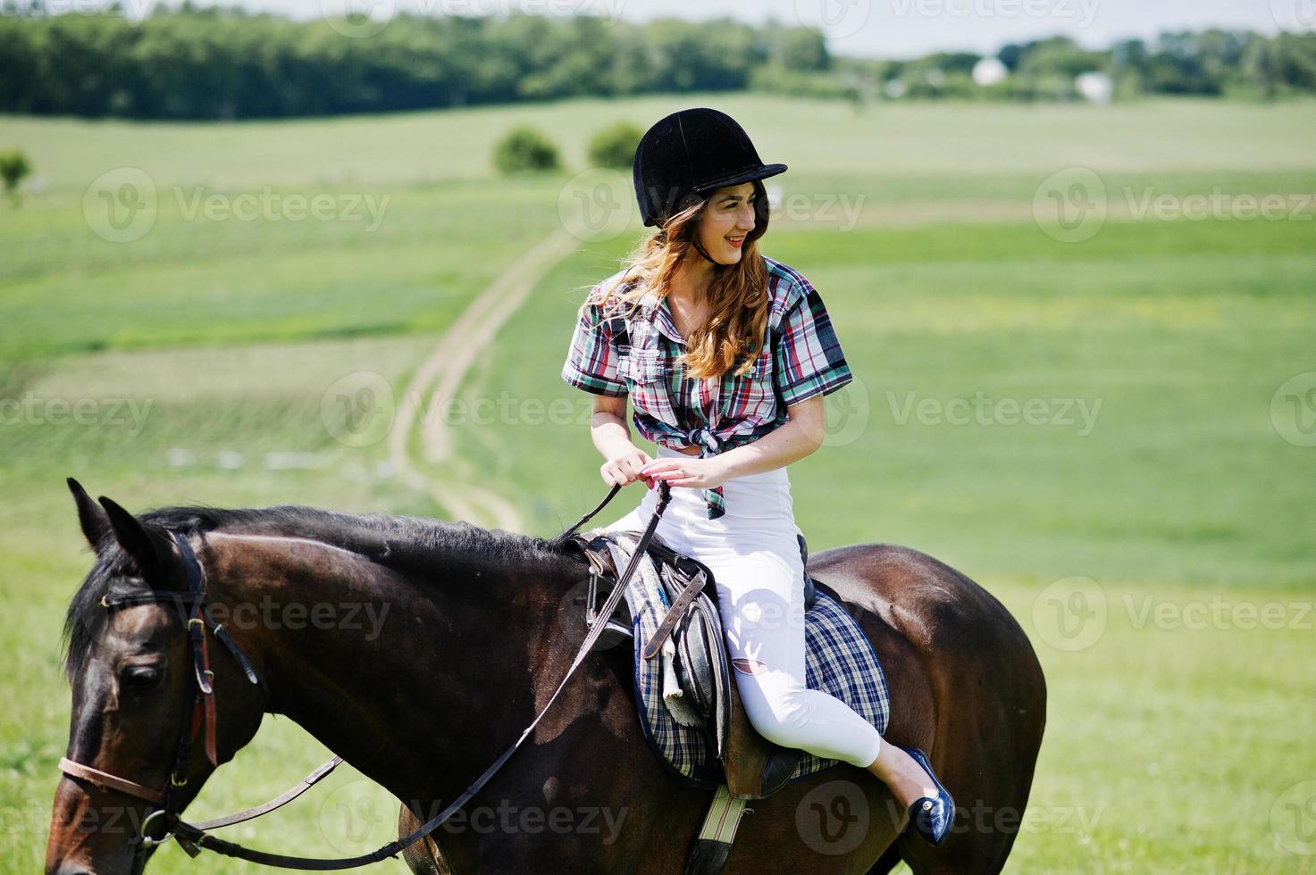 junges hübsches mädchen, das an einem sonnigen tag auf einem feld reitet. foto