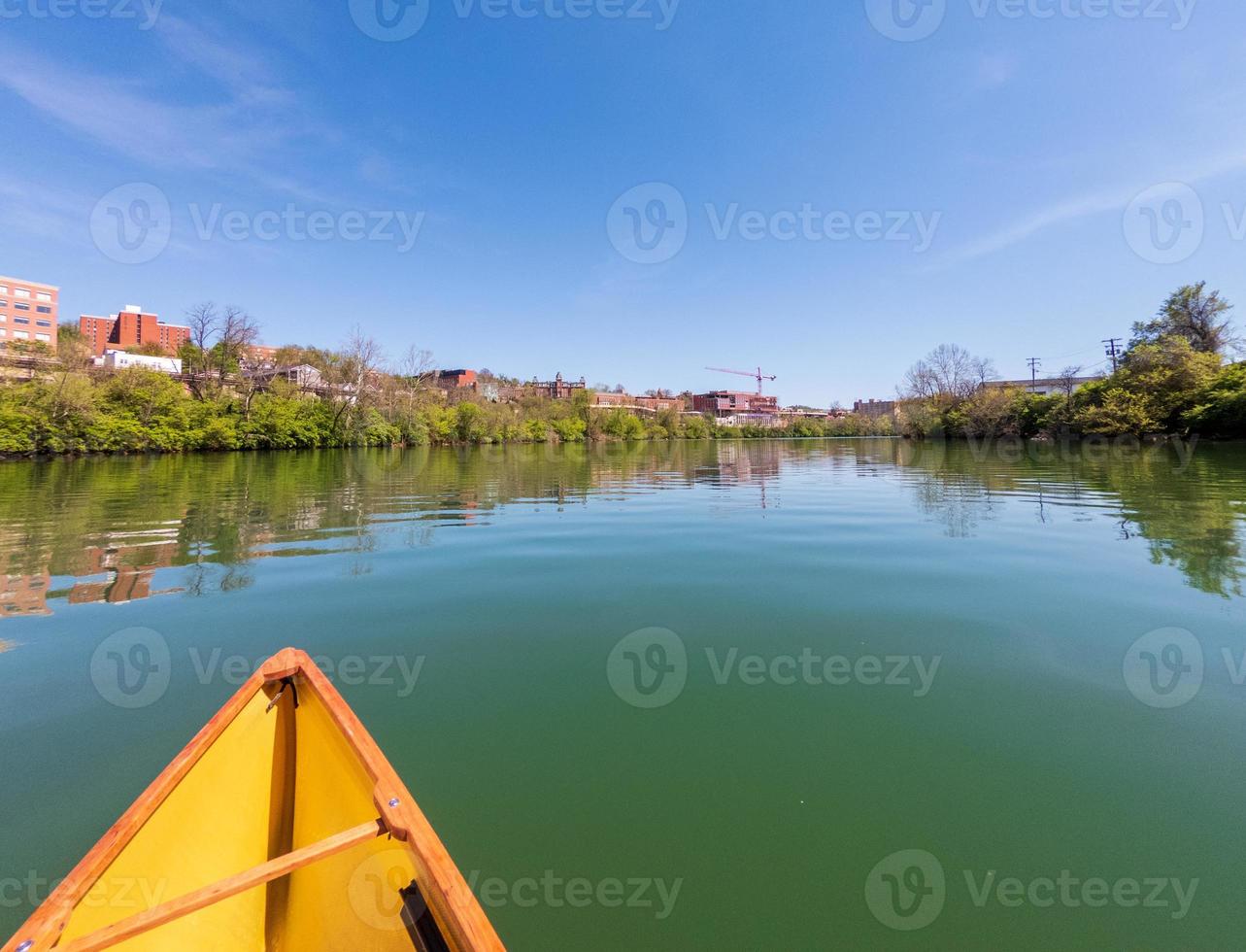 Mann in einem kleinen gelben Packkanu, der den Monongahela-Fluss in Morgantown hinaufpaddelt foto